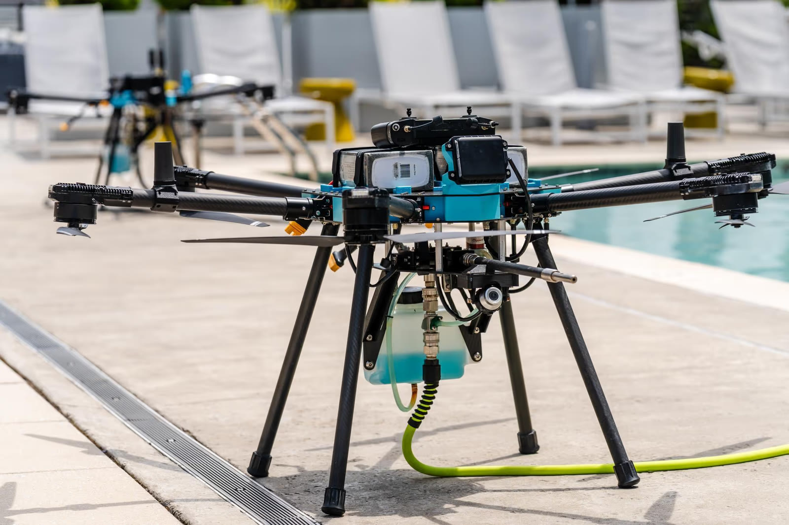 Dron industrial de Aeral limpiando la fachada de cristal de un edificio, conectado por manguera a la bomba en tierra